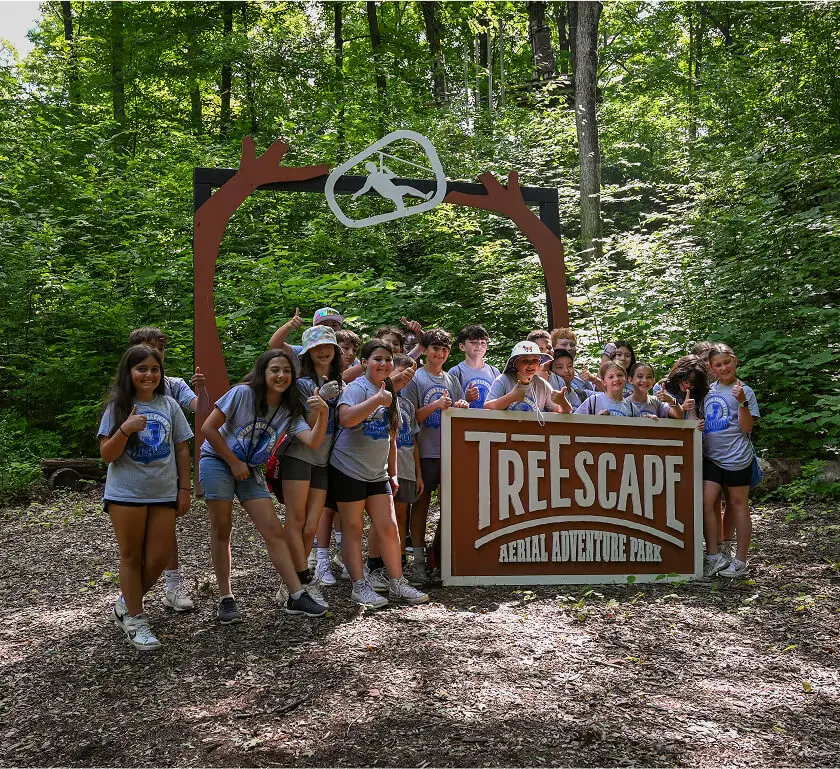 Kids participating in a youth camp at TreEscape Aerial Adventure Park in Vernon, NJ, enjoying outdoor adventure activities and rope courses in a forest setting.