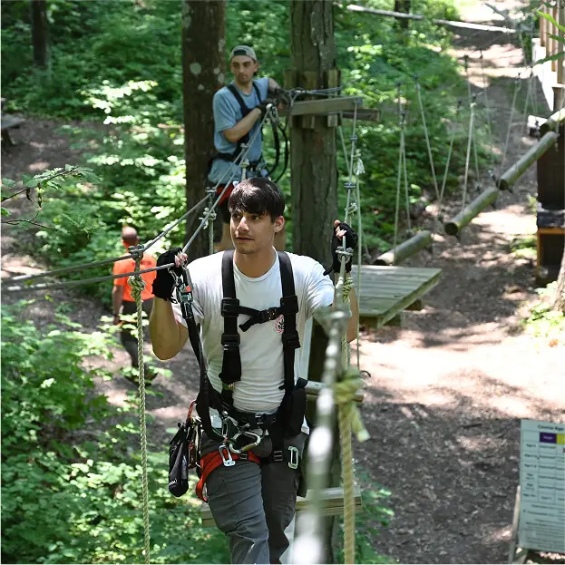 Young professionals participating in a corporate outing at TreEscape Aerial Adventure Park in Vernon, NJ, engaging in team-building activities on the ropes course.