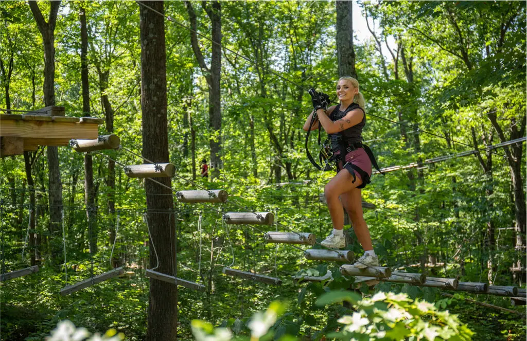 Young woman doing outdoor activities through the trees at TreEscape Aerial Adventure Park in Vernon, NJ.