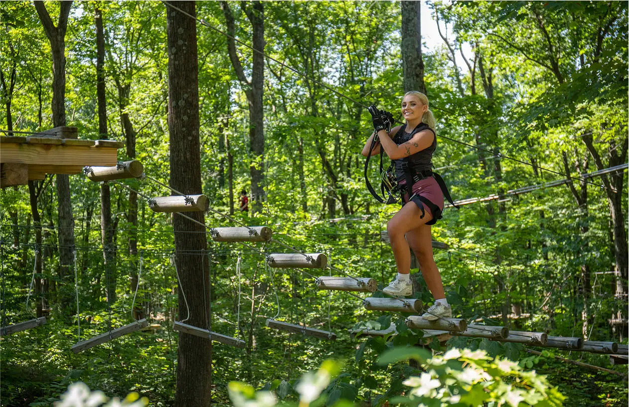 Young woman doing outdoor activities through the trees at TreEscape Aerial Adventure Park in Vernon, NJ.