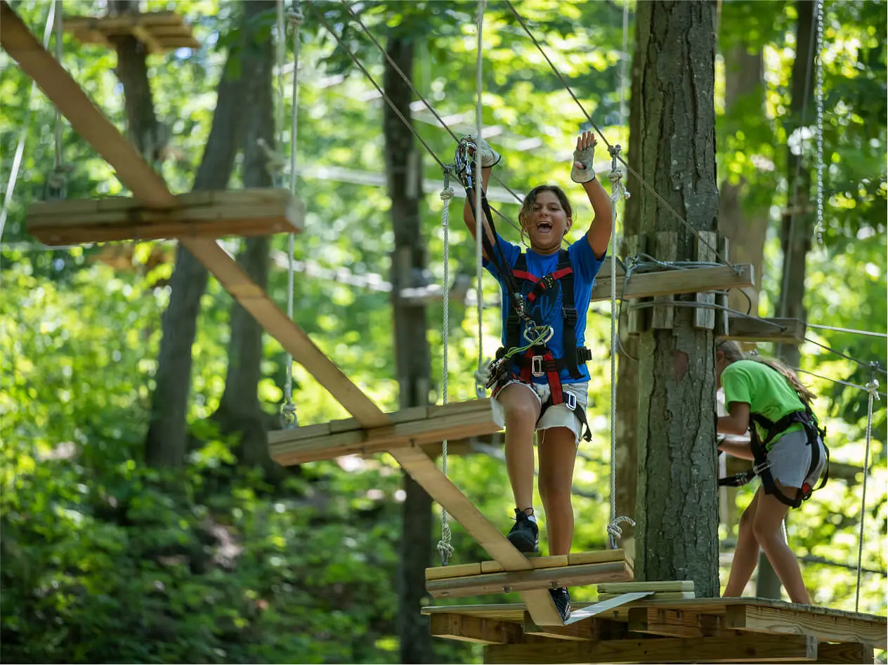 Young woman mid-zipline at TreEscape Aerial Adventure Park in Vernon, NJ, gliding between trees with a joyful expression, capturing the thrill of outdoor adventure at Great Gorge.