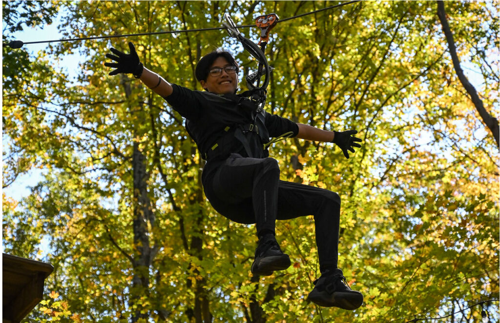Woman with eyeglasses on the zip line at TreEscape Aerial Adventure Park, Vernon, New Jersey.