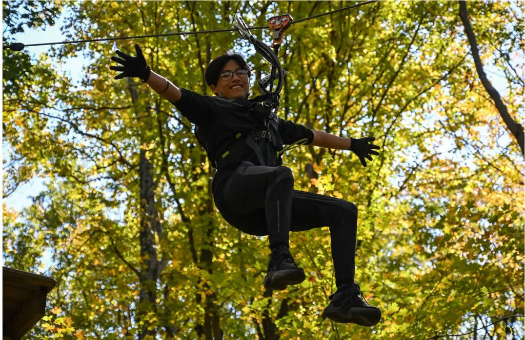 Woman with eyeglasses on the zip line at TreEscape Aerial Adventure Park, Vernon, New Jersey.