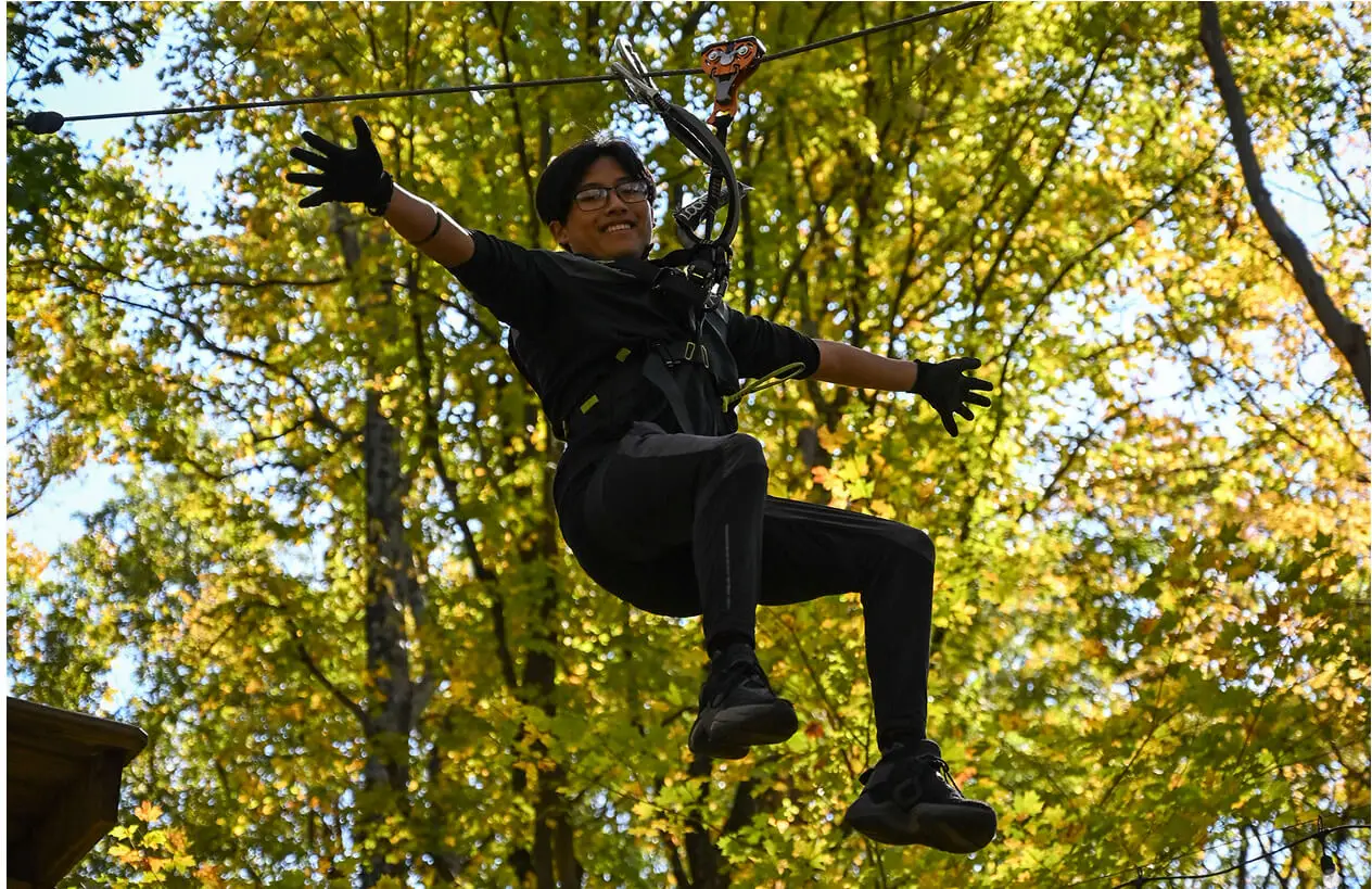 Woman with eyeglasses on the zip line at TreEscape Aerial Adventure Park, Vernon, New Jersey.