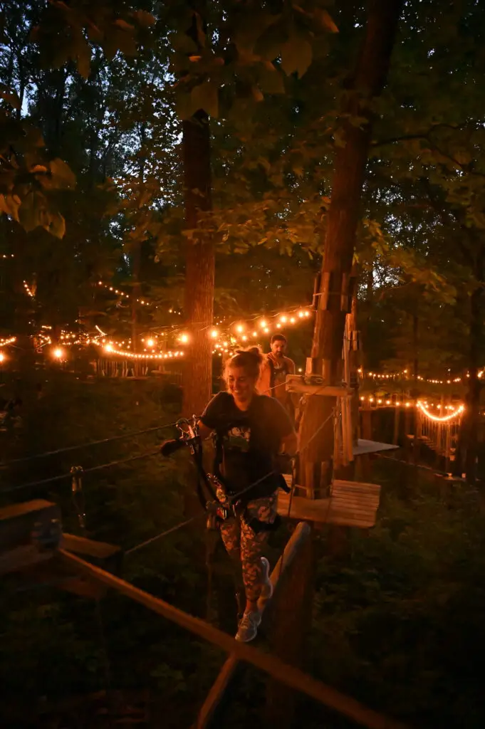 Woman participating in a nighttime ropes course at TreEscape Vernon, NJ> 