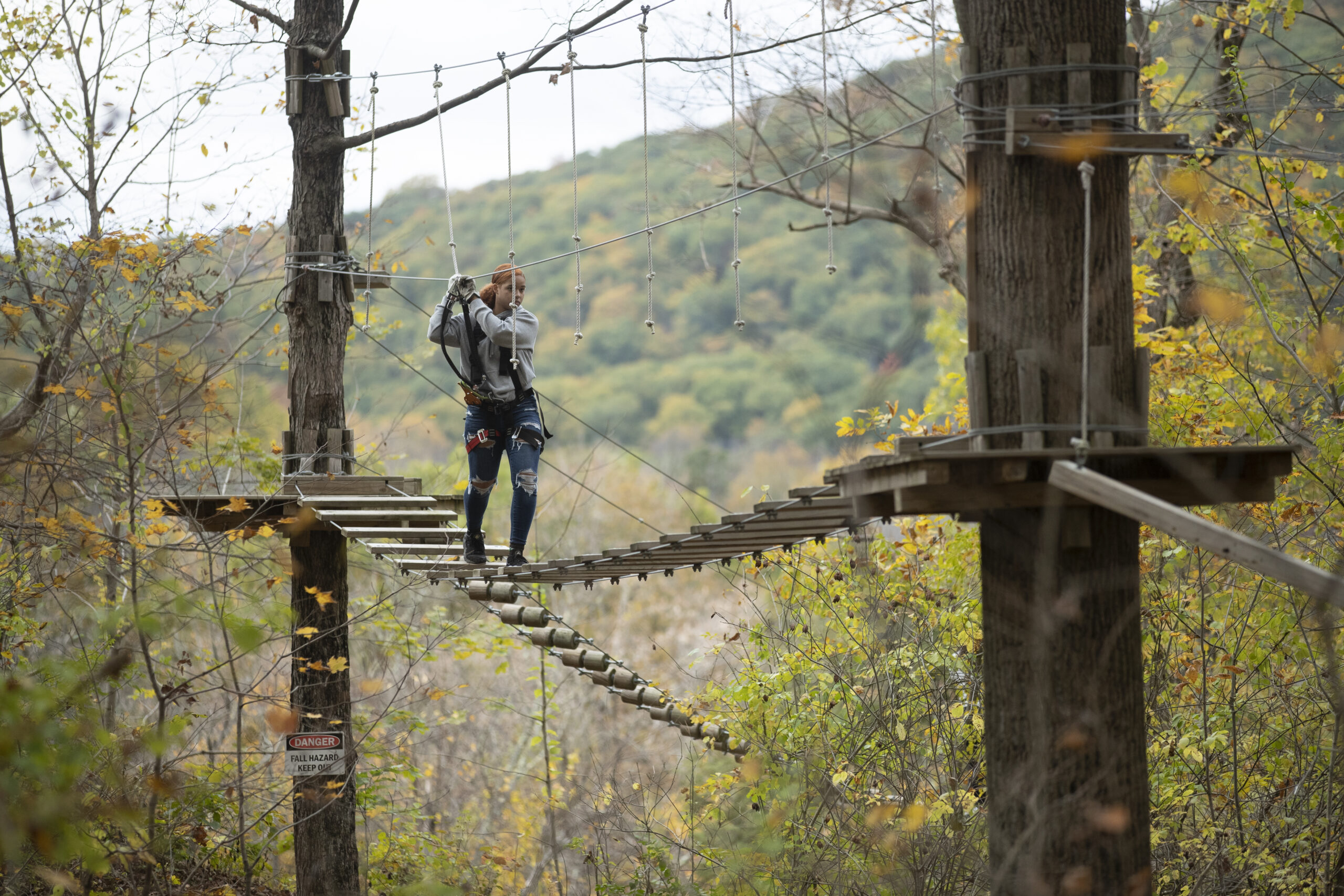 Woman navigating an aersil ropes course at TreEscape Aerial Adventure park, as a symbol of places in New Jersey to visit this fall. Fall activities NJ.