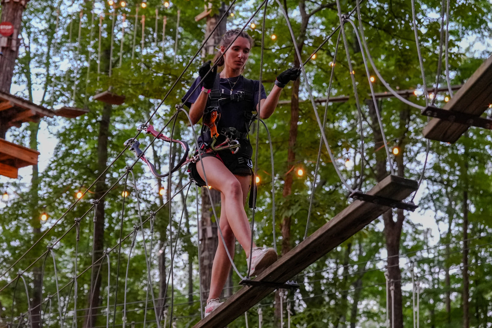 Woman navigating a ropes course at TreEscape by night 