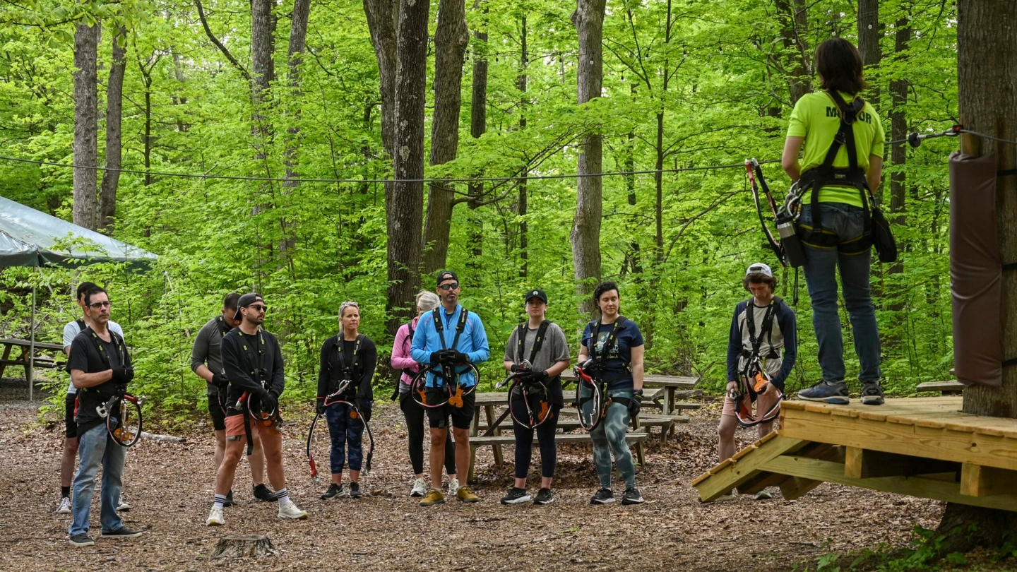 Group of young people at TreEscape Adventure Park, preparing for zip line in teh forest